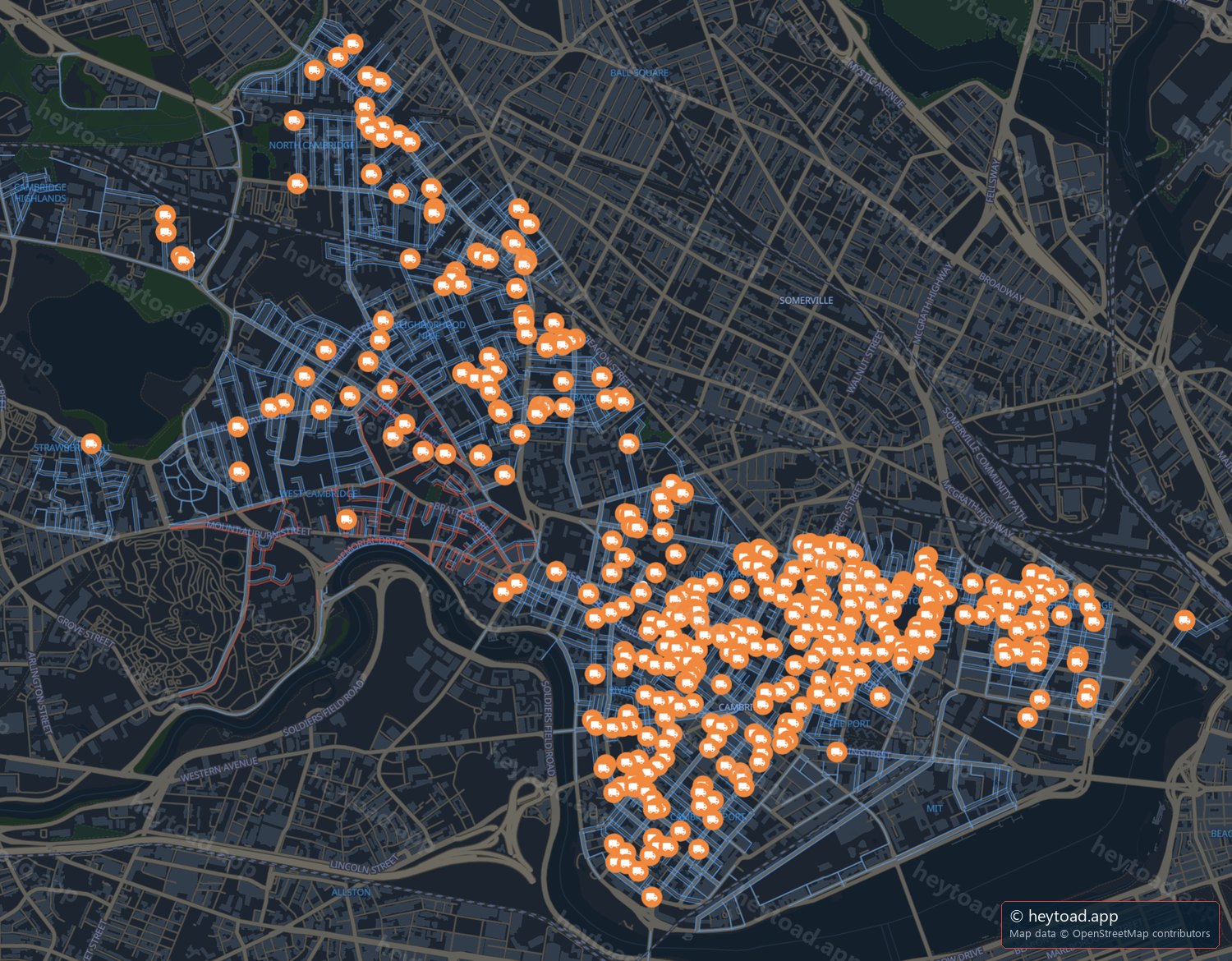 Map of Cambridge with an orange truck pin on every block holding a moving permit. Pins concentrate east of Harvard Square and south of Broadway through Cambridgeport, Mid-Cambridge and The Port, with a thinner line running northwest along Massachusetts Avenue to North Cambridge. Somerville, at the top right, has no pins.